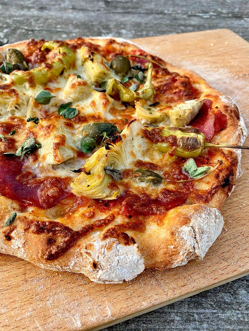 Meine persönliche Variante der Capricciosa ist die Pizza Rolfe mit San-Marzano-Tomaten, Salami, Artischocken, Apfelkapern, Peperoncini, gelbe Peperoni, Mozzarella und Oregano. Pizzateig selber machen.